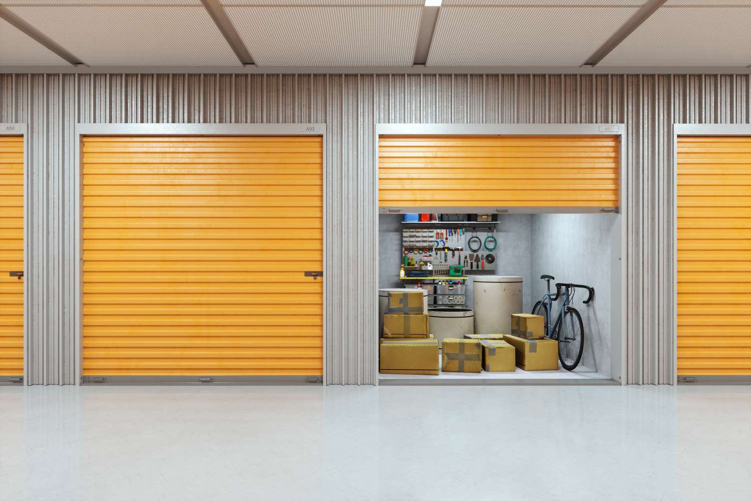 A storage unit with the door partly open revealing packed boxes a bicycle and organized shelves with various tools and items