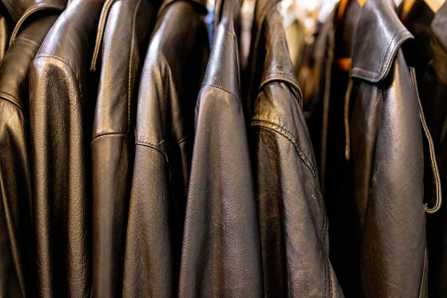 A row of hanging leather jackets on a clothing rack