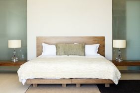 A minimalist bedroom with a wooden bed frame white bedding and two bedside lamps