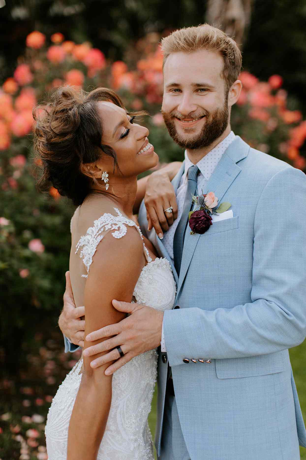 wedding couple posing for portrait in front of flowering bushes