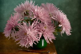 A bouquet of flowers in a green vase on a wooden table