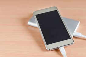 Smartphone charging on a power bank placed on a wooden surface