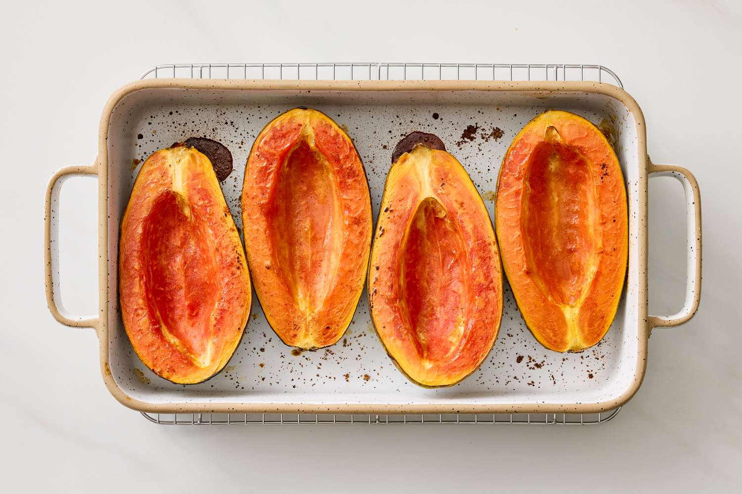 Halved roasted papayas on a baking tray