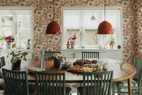A dining table set with food and drinks surrounded by green chairs in a welllit room