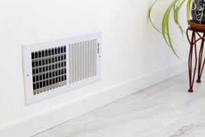 Wall vent cover on an interior wall near a plant