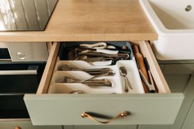 An open kitchen drawer containing utensils in organizational compartments
