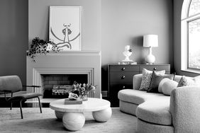 Modern living room interior with black-and-white decor, arched window, styled fireplace, furniture, and wall art