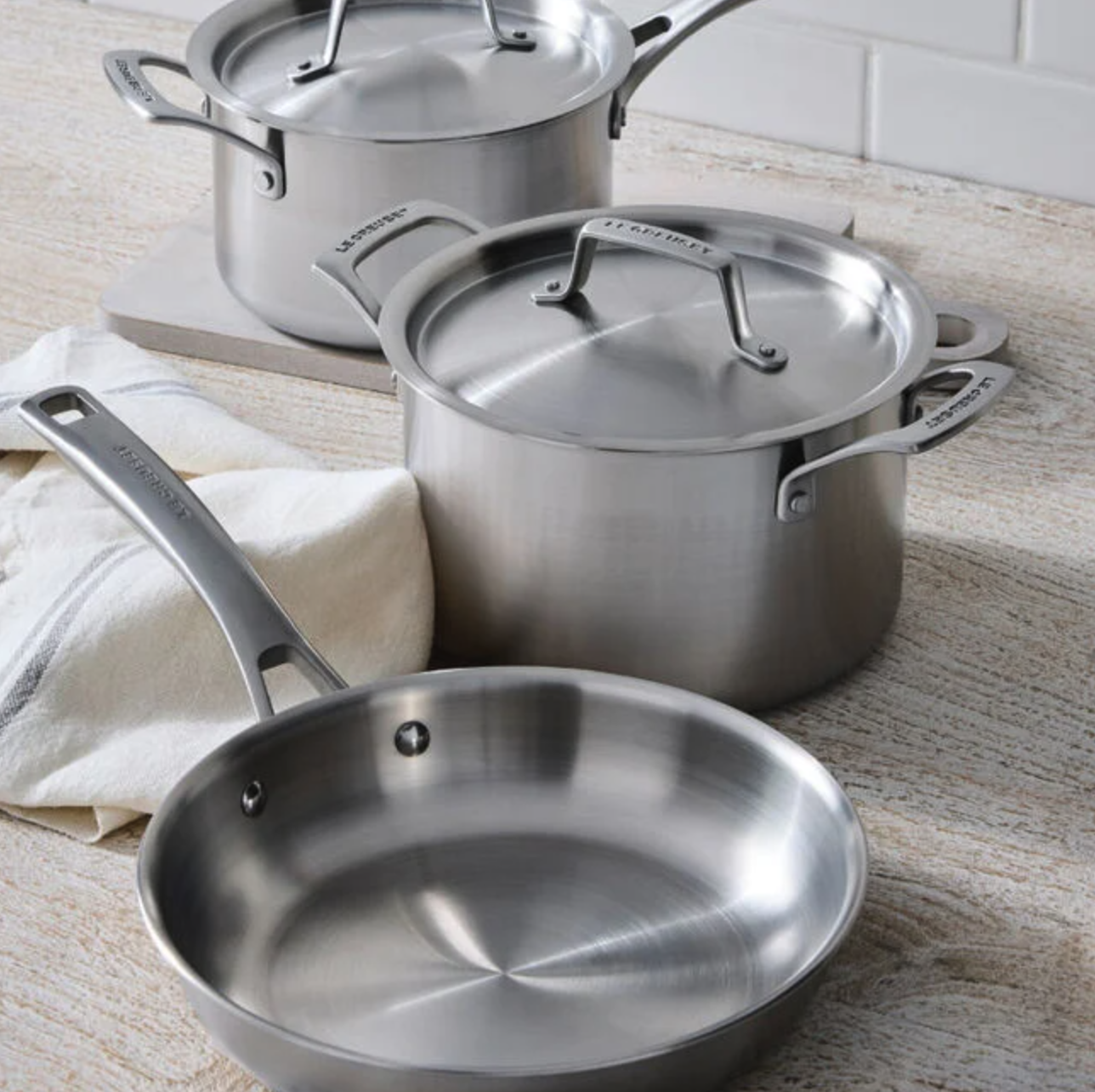 Cookware set including saucepan, stockpot, and skillet on a kitchen surface