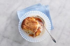 portion of peach cobbler in small bowl with cream and spoon