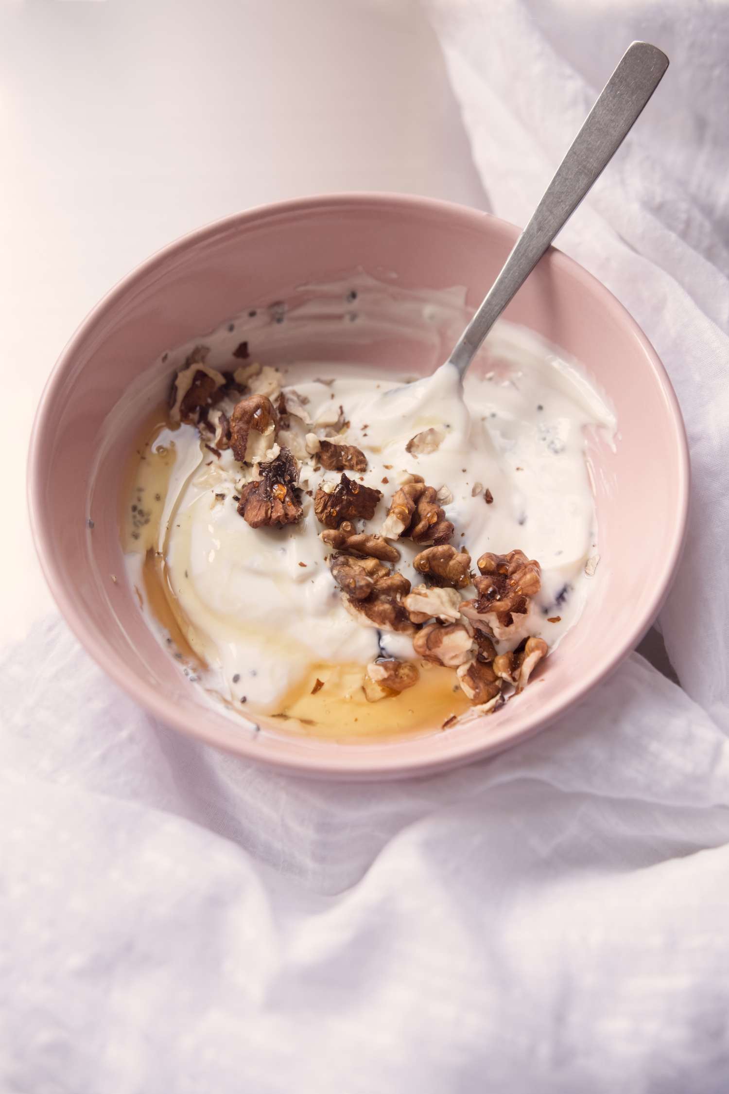yogurt with walnuts and honey in pink bowl