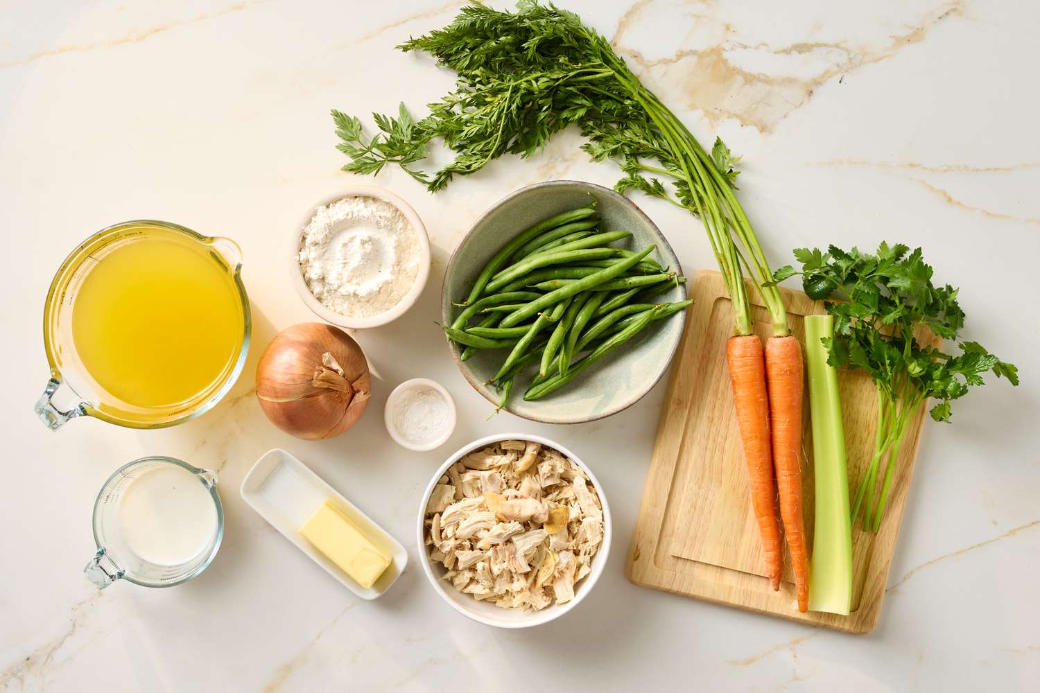 Ingredients for chicken and dumplings including chicken vegetables broth milk butter flour and seasoning