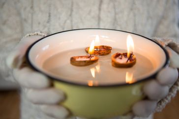 Person holding a bowl with floating candles made from nutshells