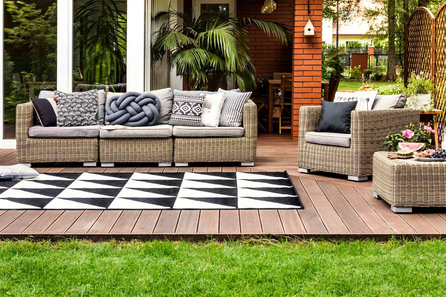 rattan couch with pillows and rug on backyard patio