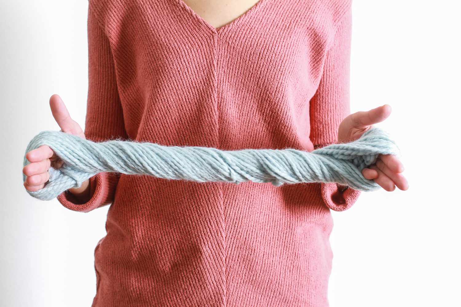 wrapped blue yarn twisted between hands