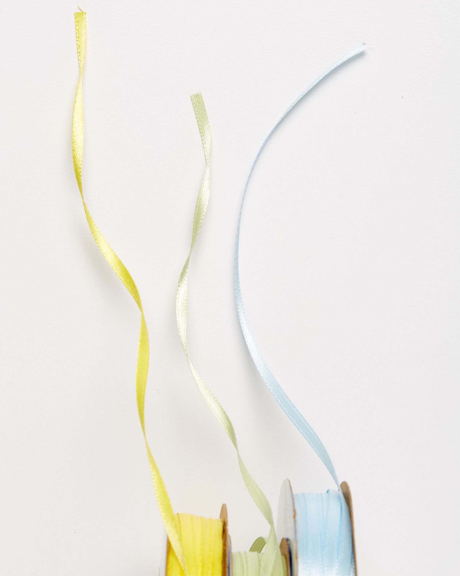 three spools of colorful embroidery ribbon against a white background