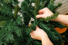 Hands adjusting branches on an artificial tree