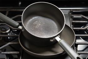 Two cooking pots one stacked inside the other sitting on a stovetop with visible scuffs and scratches on their surfaces