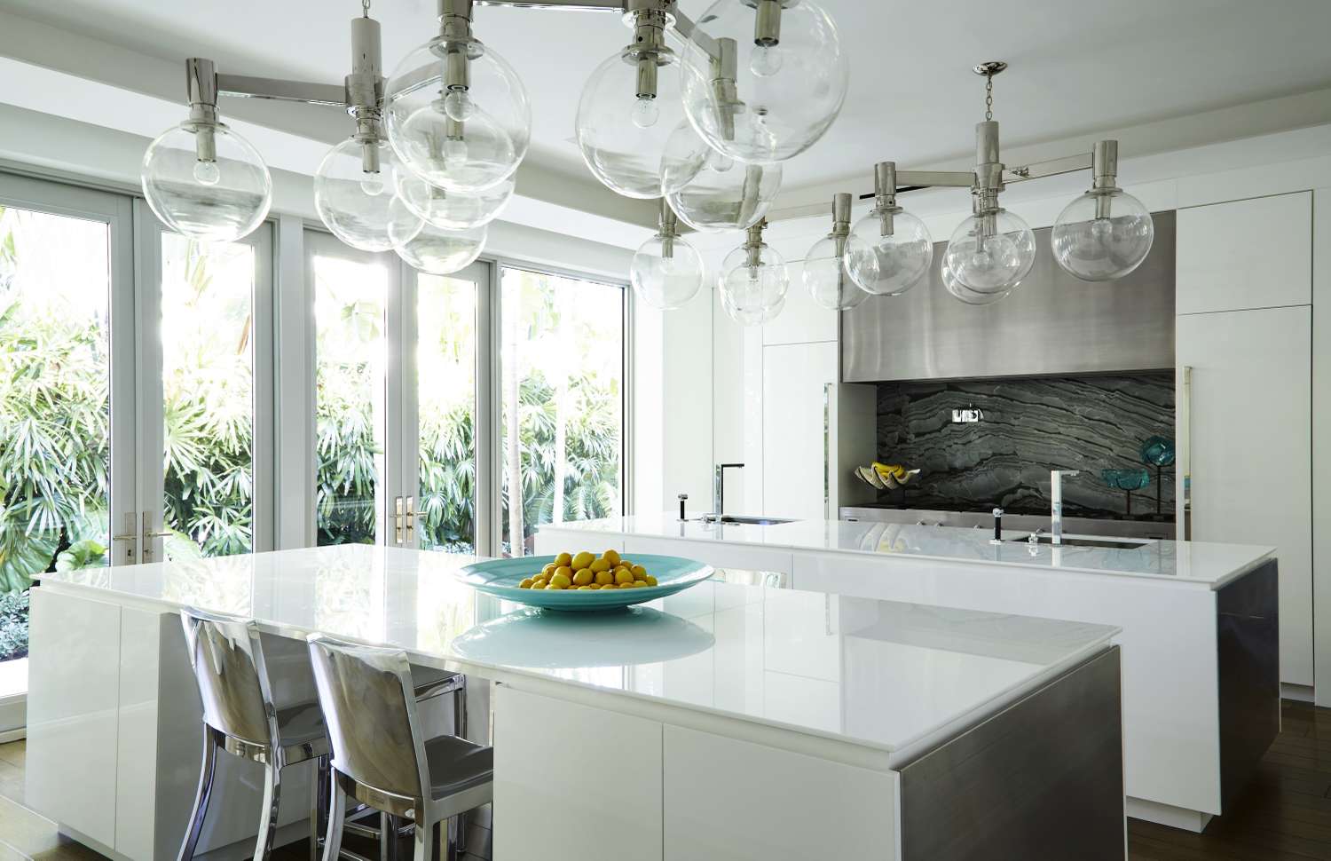 Modern kitchen interior with a marble backsplash globe pendant lights and sleek white countertops