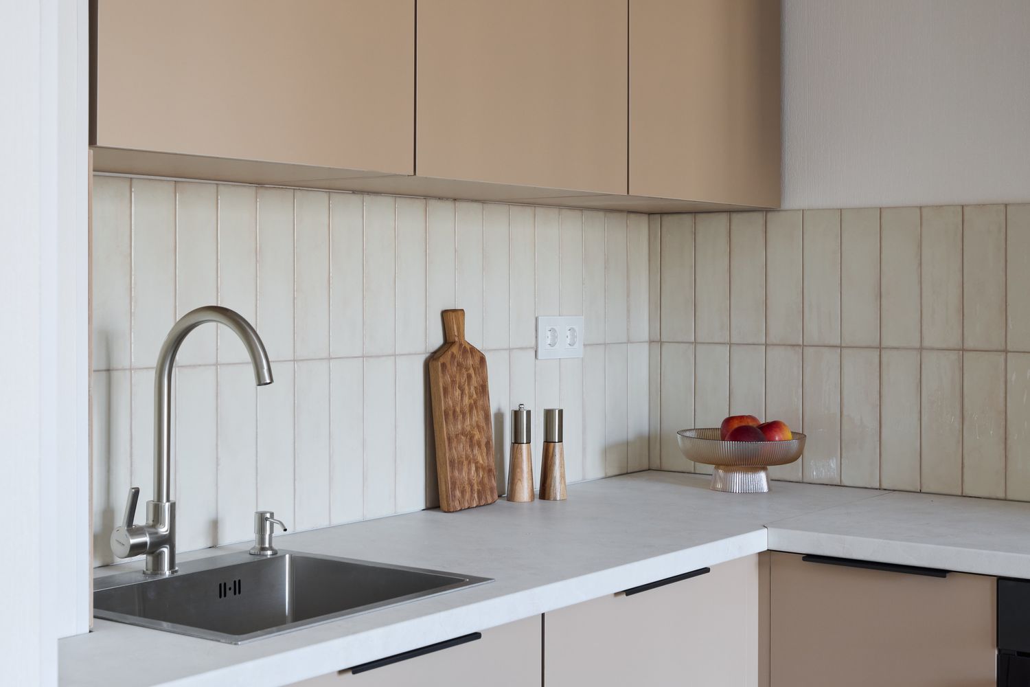 Modern kitchen counter with a sink wooden cutting board and a bowl of fruit on display