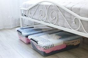 Plastic storage boxes filled with clothing under a metalframed bed