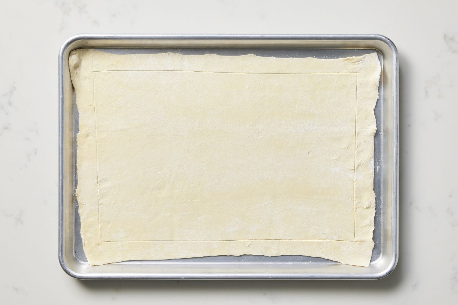 Scored pastry dough on baking sheet