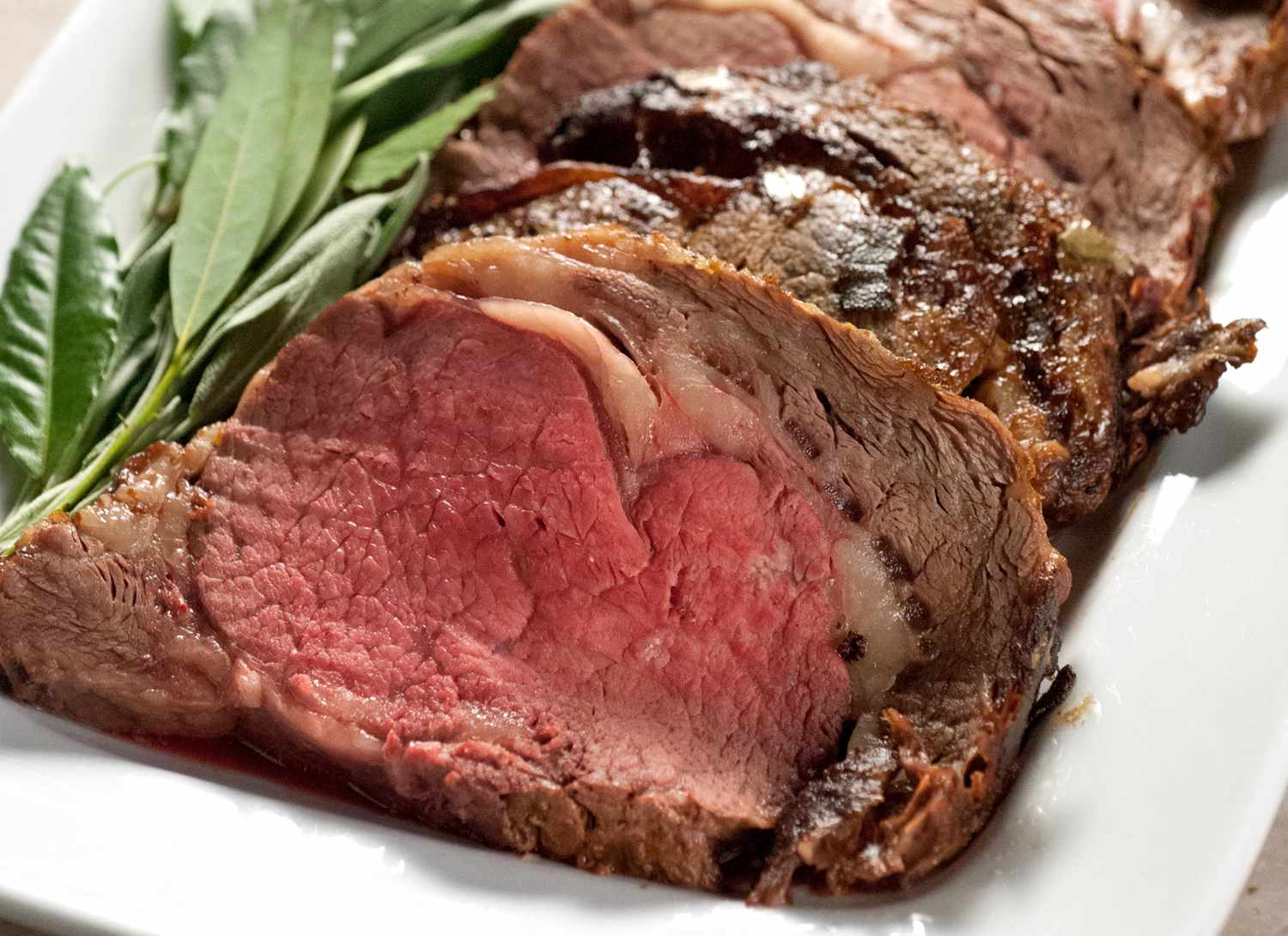 roast prime rib on a white plate with green garnish