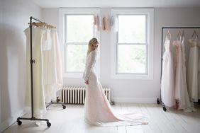 A woman in a bridal gown standing in a showroom with other dresses on racks