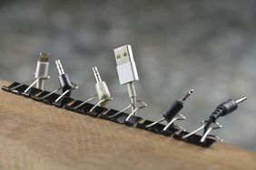 Various cables held upright by binder clips on a wooden surface