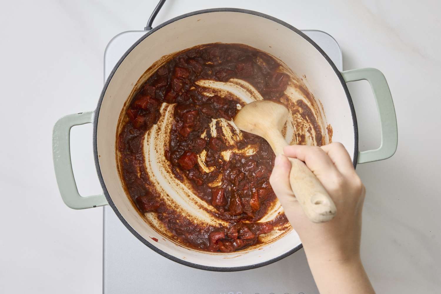 Person stirring chicken tortilla soup in a pot on a stovetop