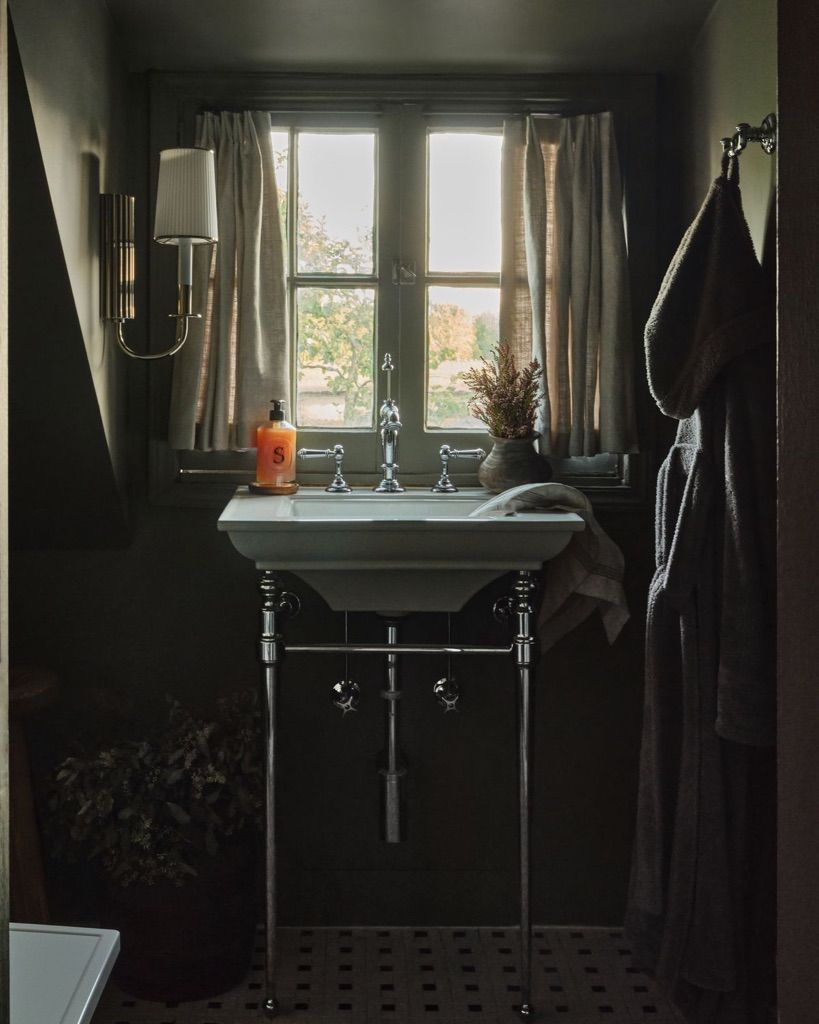Bathroom with a vintage sink curtained window and hanging robes