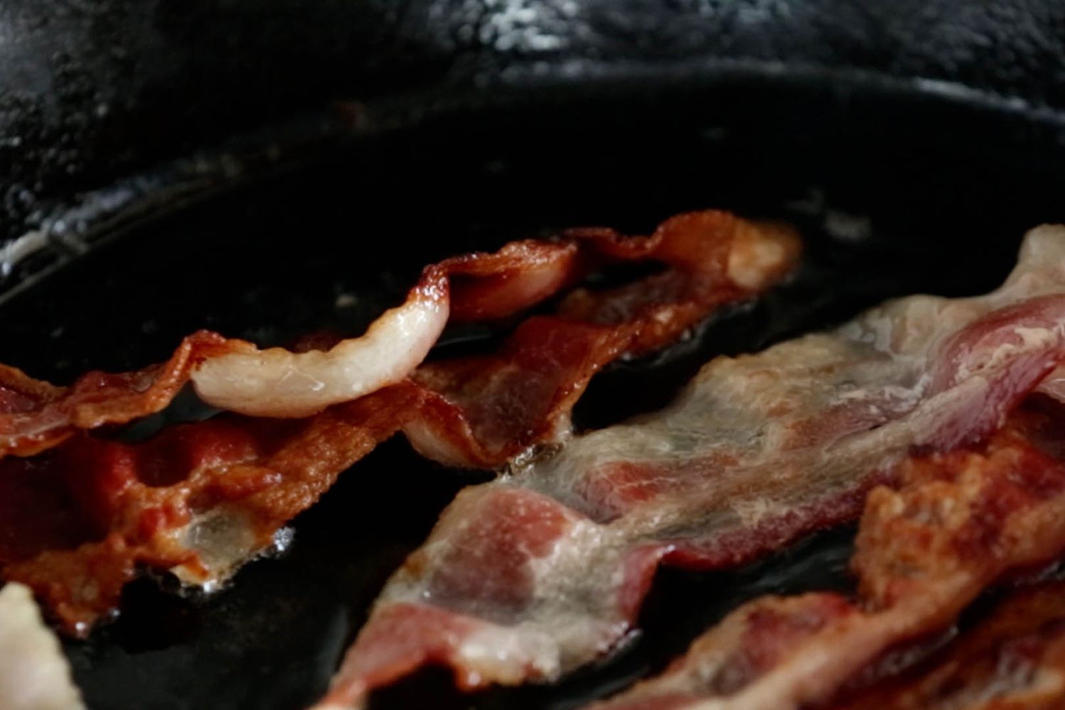 bacon frying in cast iron pan