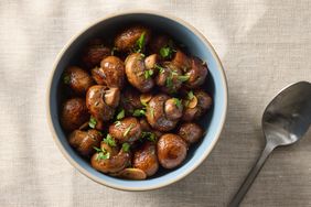 Bowl of sauted mushrooms garnished with herbs next to a spoon