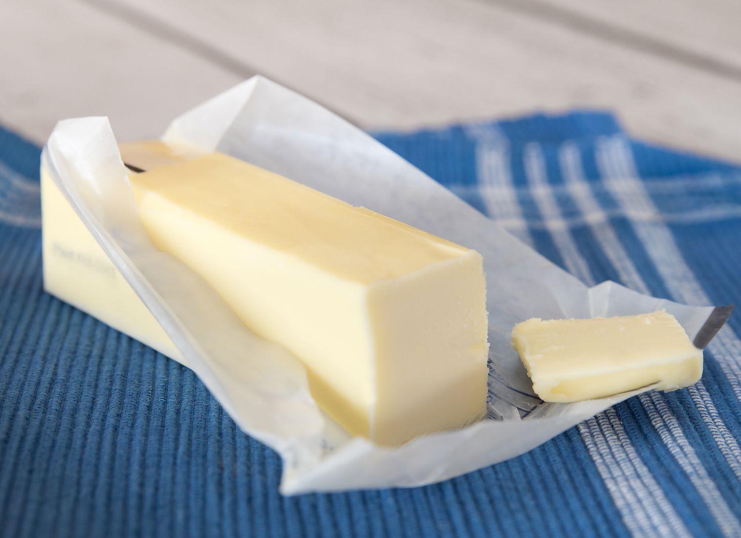 stick of butter partially unwrapped on blue napkin