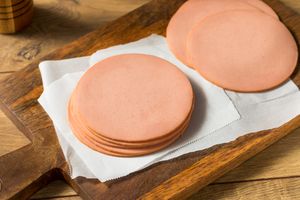 Slices of bologna on a wooden board with parchment paper