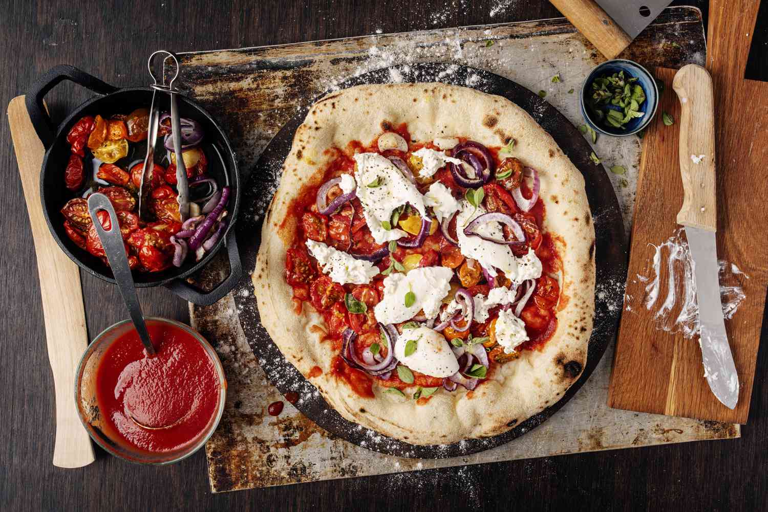 pizza with burrata, tomatoes, and red onions on baking sheet