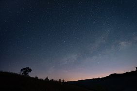 Starfilled night sky above a silhouette of hills and trees a serene astronomical view