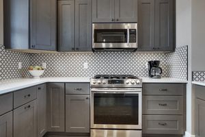 Modern kitchen with dark cabinets stainless steel appliances and patterned tile backsplash