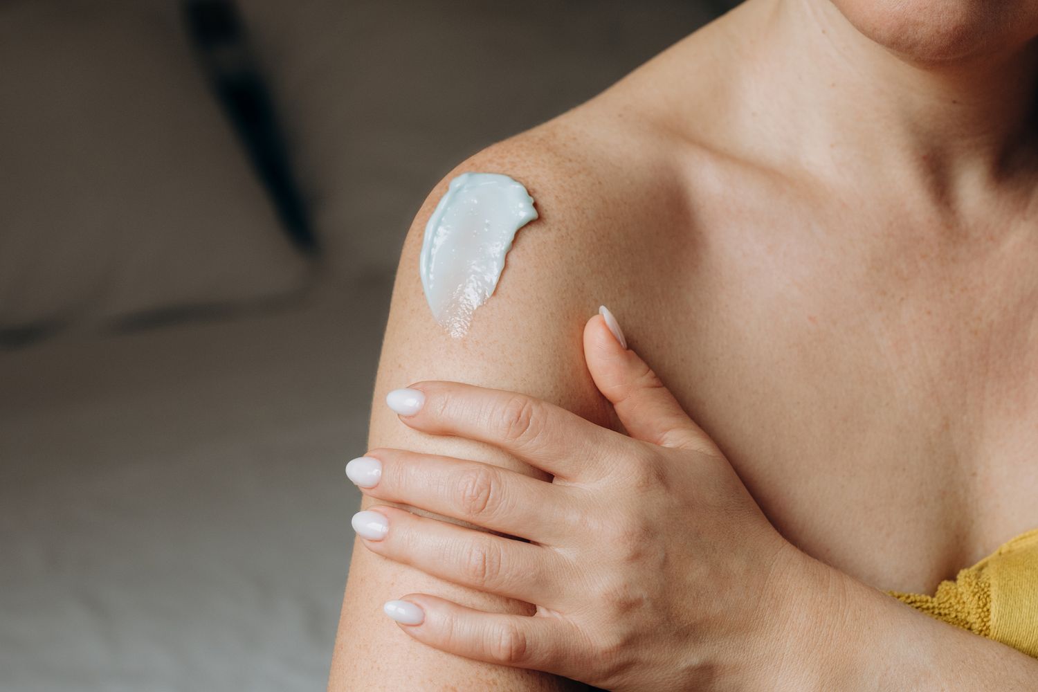 A person applying cream to their shoulder