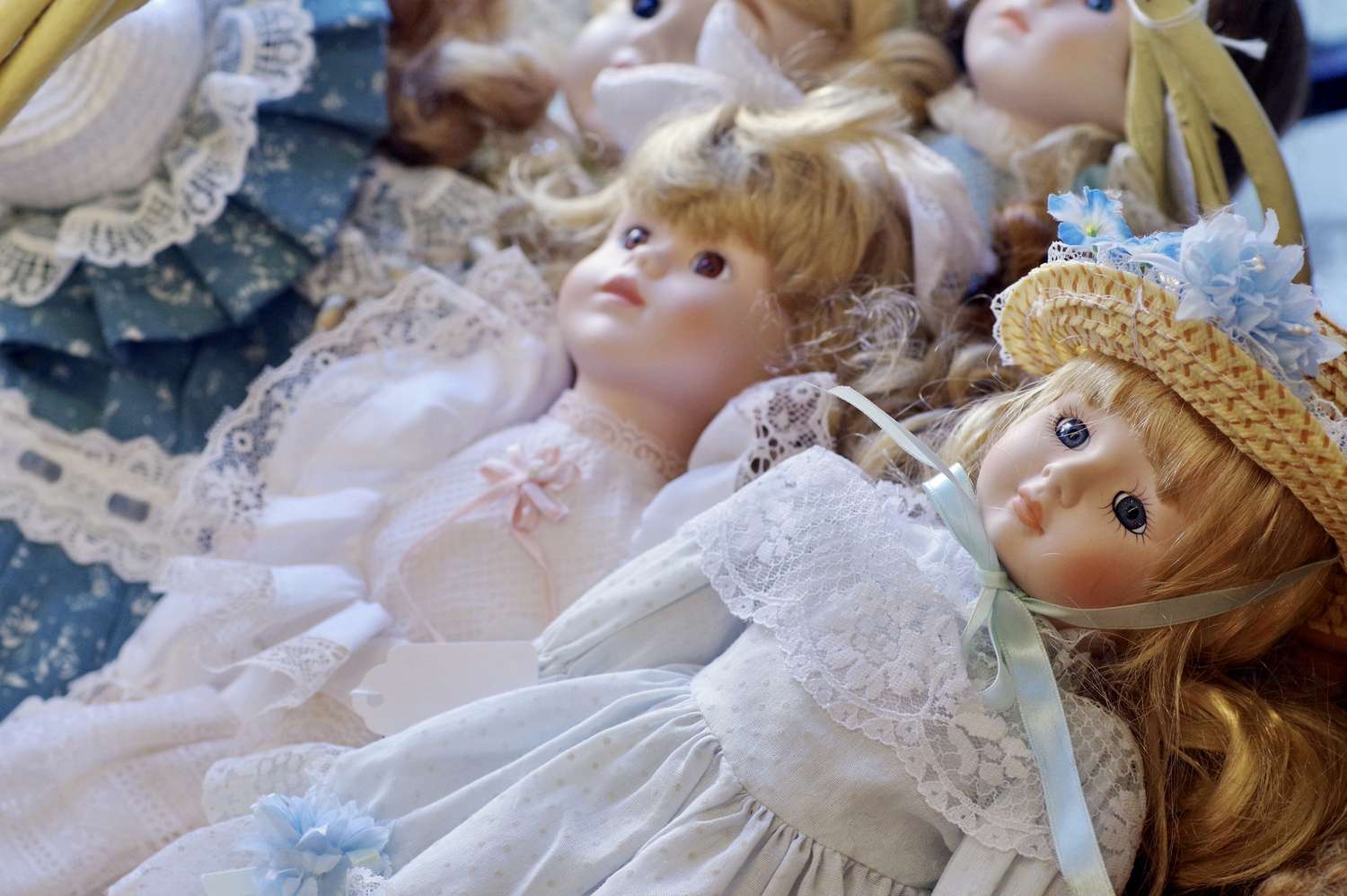 A collection of porcelain dolls arranged closely together some with lace and hats