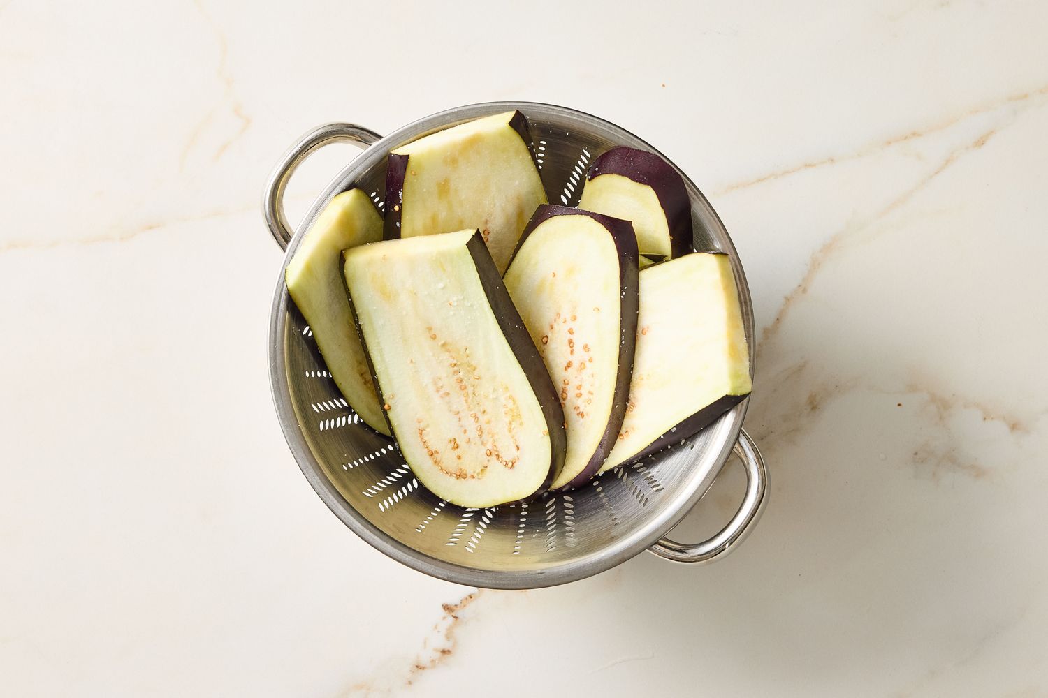 Sliced eggplants in a metal colander