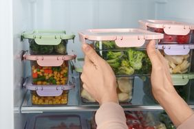 Woman taking container with broccoli from refrigerator