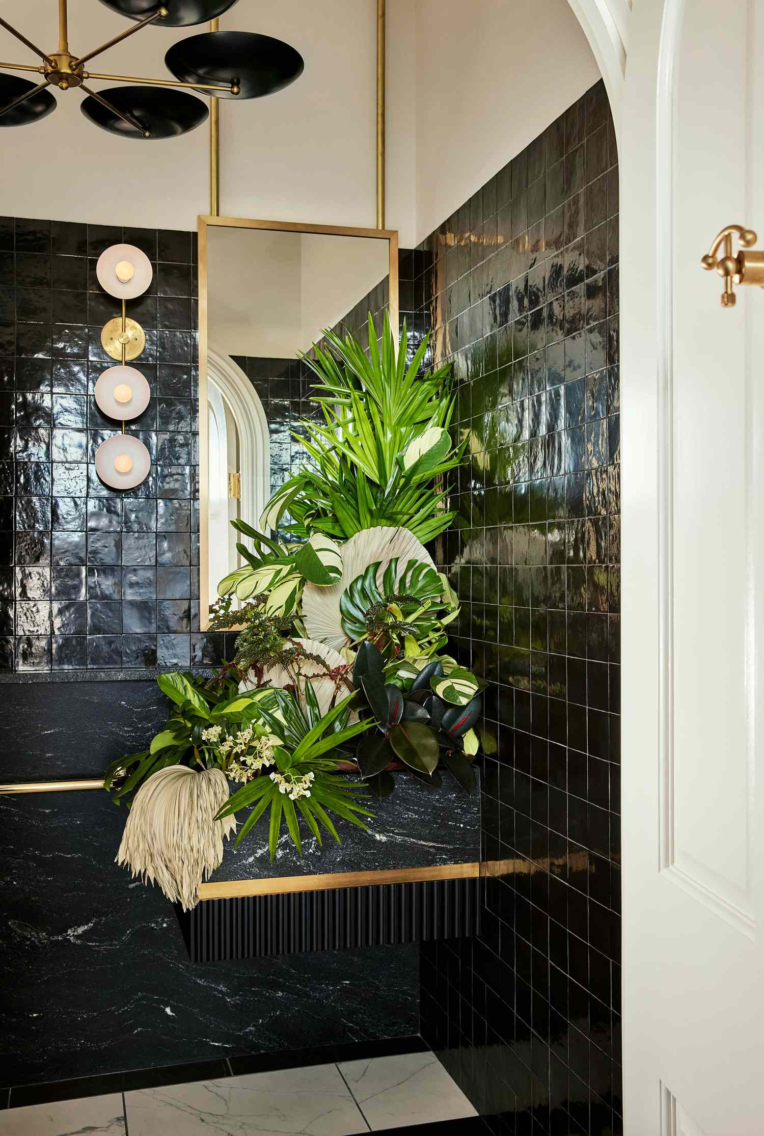 Bathroom with dark tiles gold accents and green plants as decorations