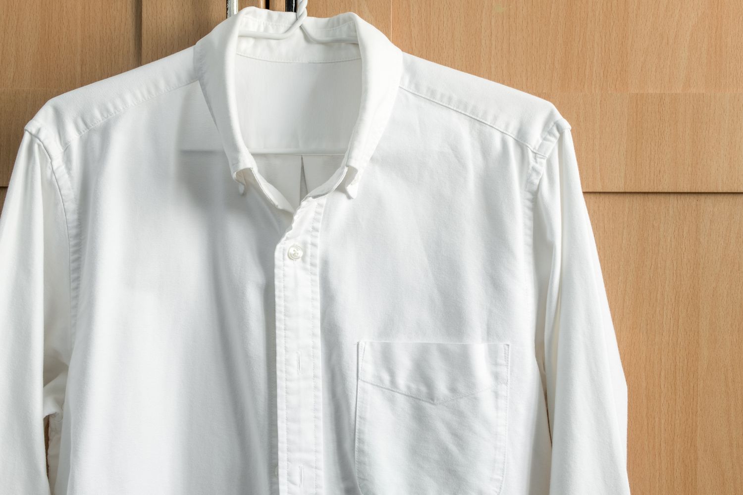 White shirt with long sleeves hanging on wardrobe