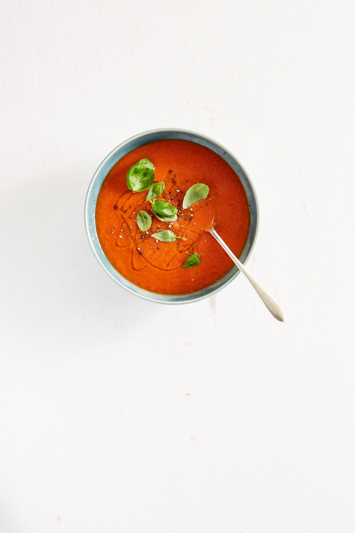 tomato soup in bowl with basil leaves garnish