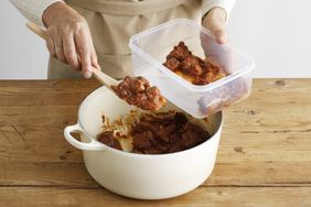 Person transferring cooked food from a pot to a storage container
