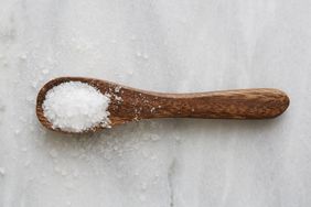 A wooden spoon with coarse salt on a light surface