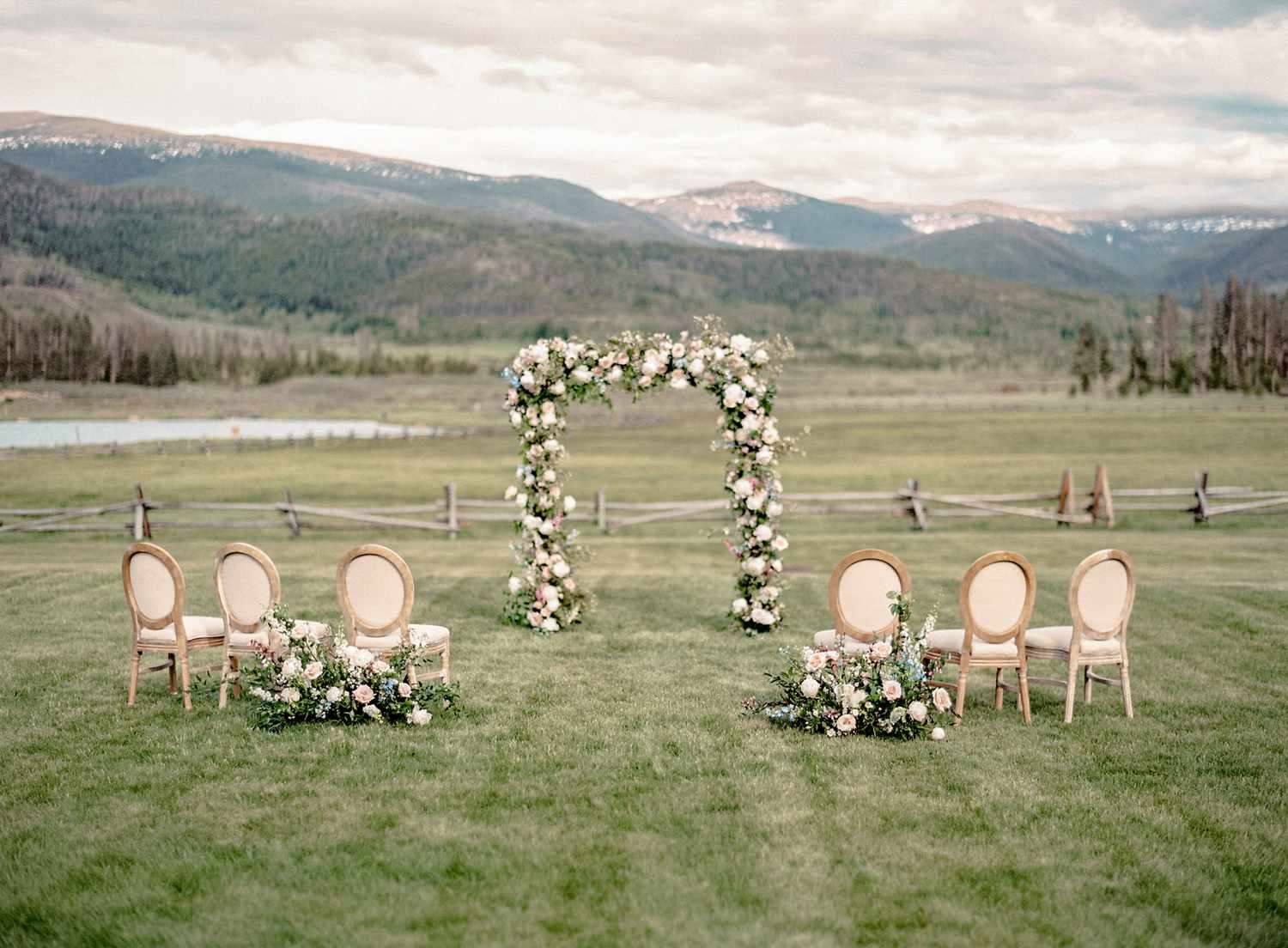 small wedding ceremony setting with floral arch against mountain backdrop