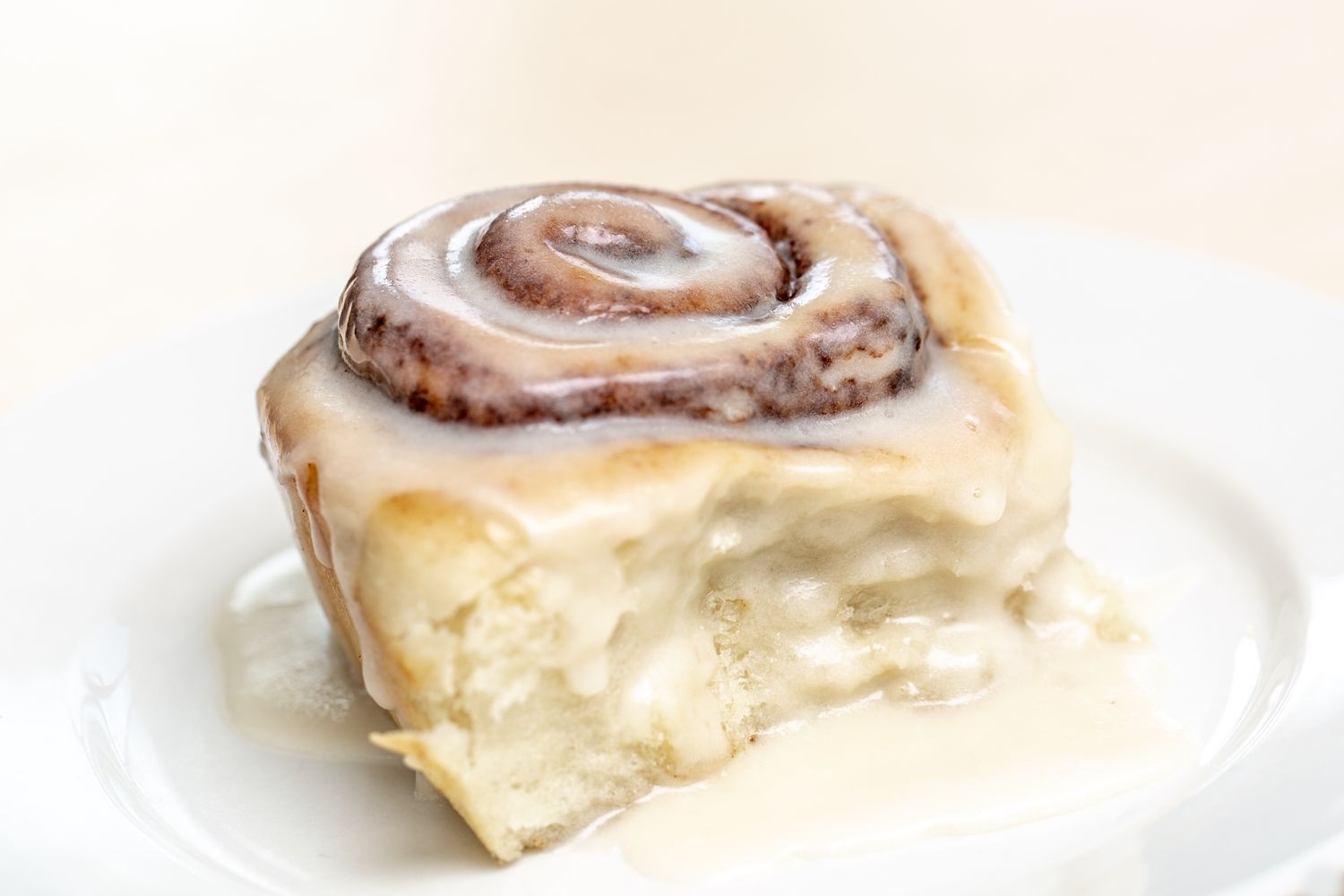 A glazed cinnamon roll served on a white plate