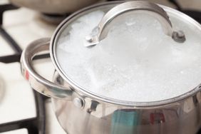 Cooking pot with lid foaming from boiling liquid on stovetop