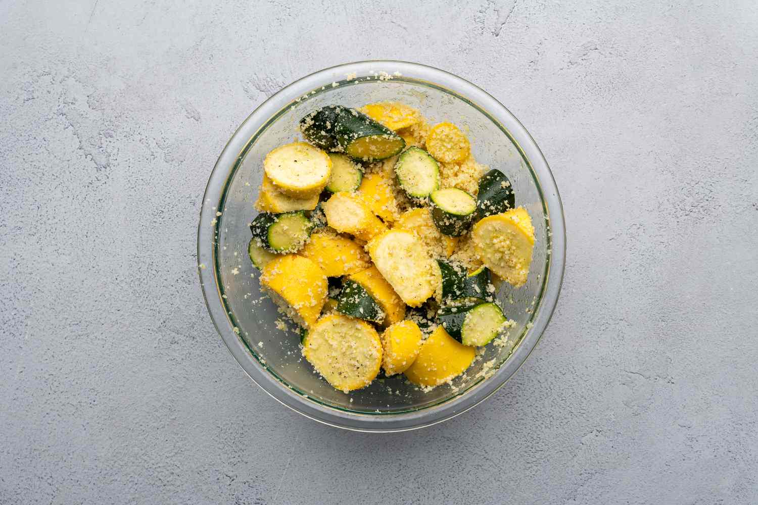 sliced summer squash and zucchini tossed with parmesan in a bowl 